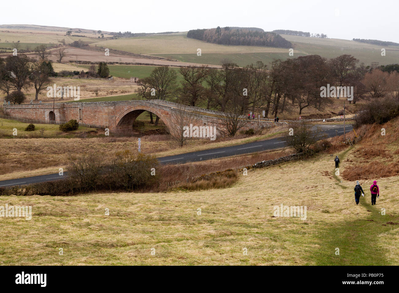 Menschen, die während einer Schneeflut auf St Cuthbert's Way, einem Fußweg in der Landschaft von Northumberland, England, wandern. Stockfoto