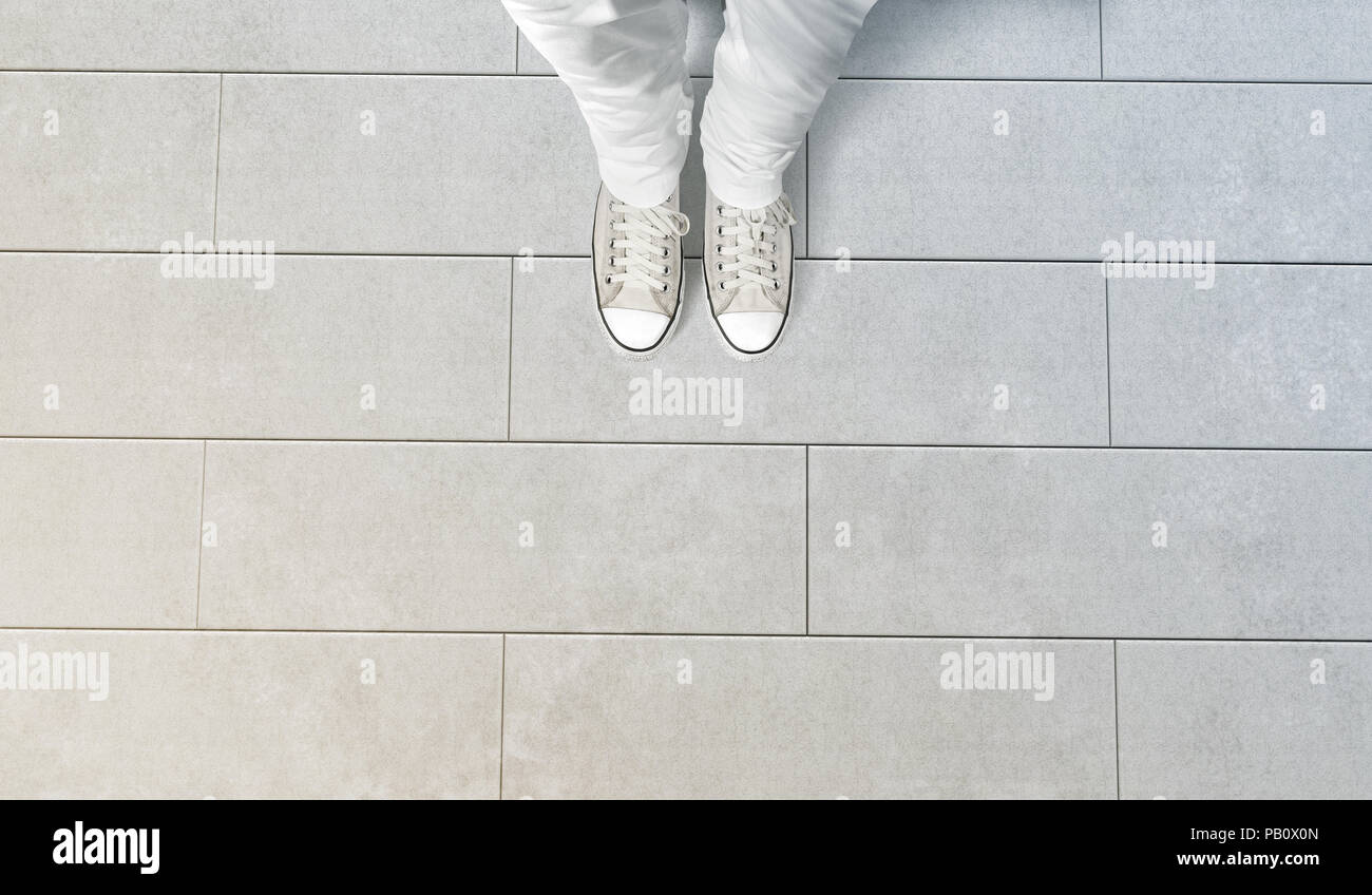 Person, die Foto von seinen Füßen stehen auf Betonboden, isoliert, Ansicht von oben, clipping path. Boden design Mock up. Mann tragen Gumshoes und nach unten Stockfoto