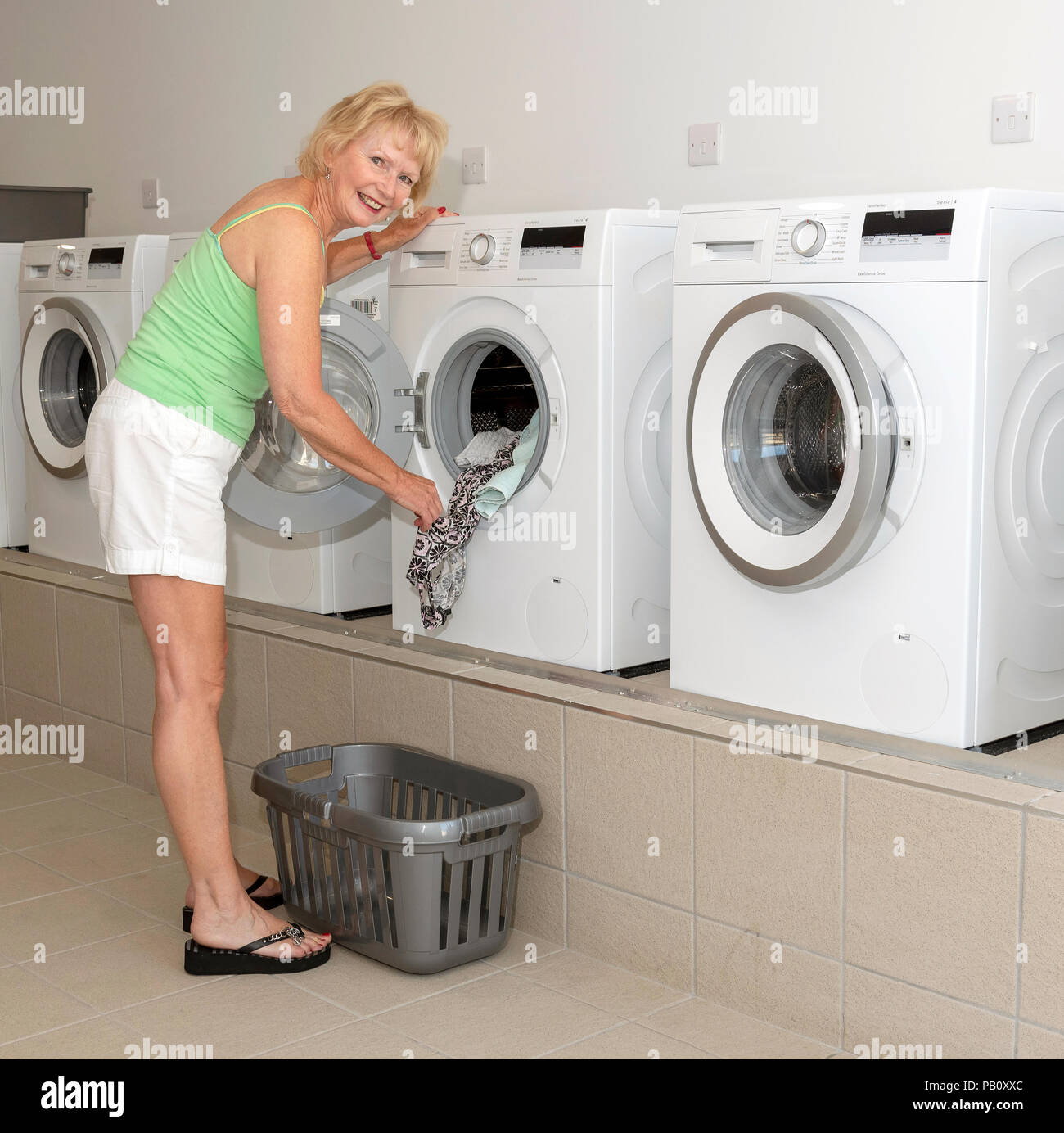 Eine Frau mit einer Waschmaschine im Hauswirtschaftsraum, Stockfoto