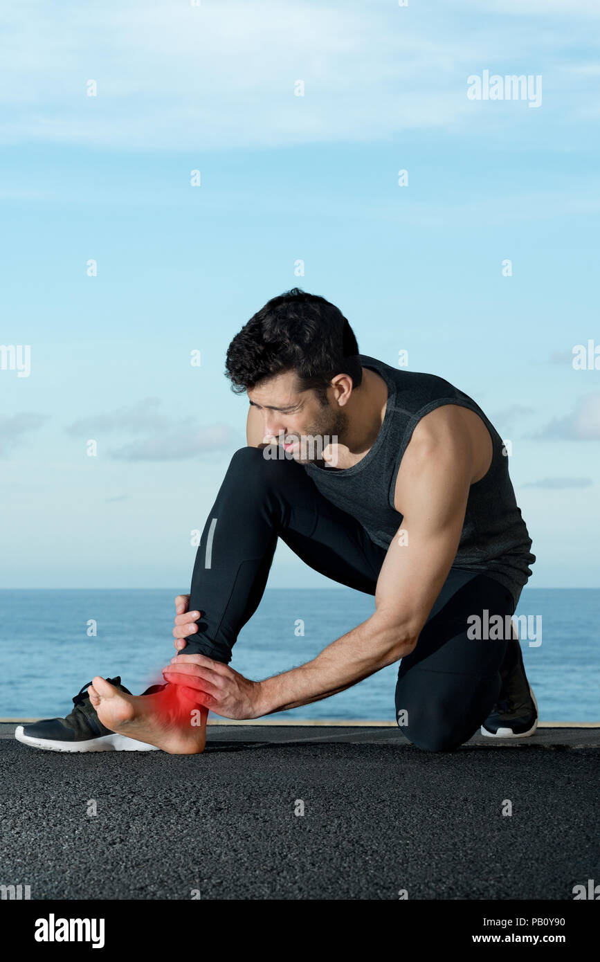 Athlet mit Knöchel Schmerzen im Hintergrund mit Meerblick Platz für Text Stockfoto