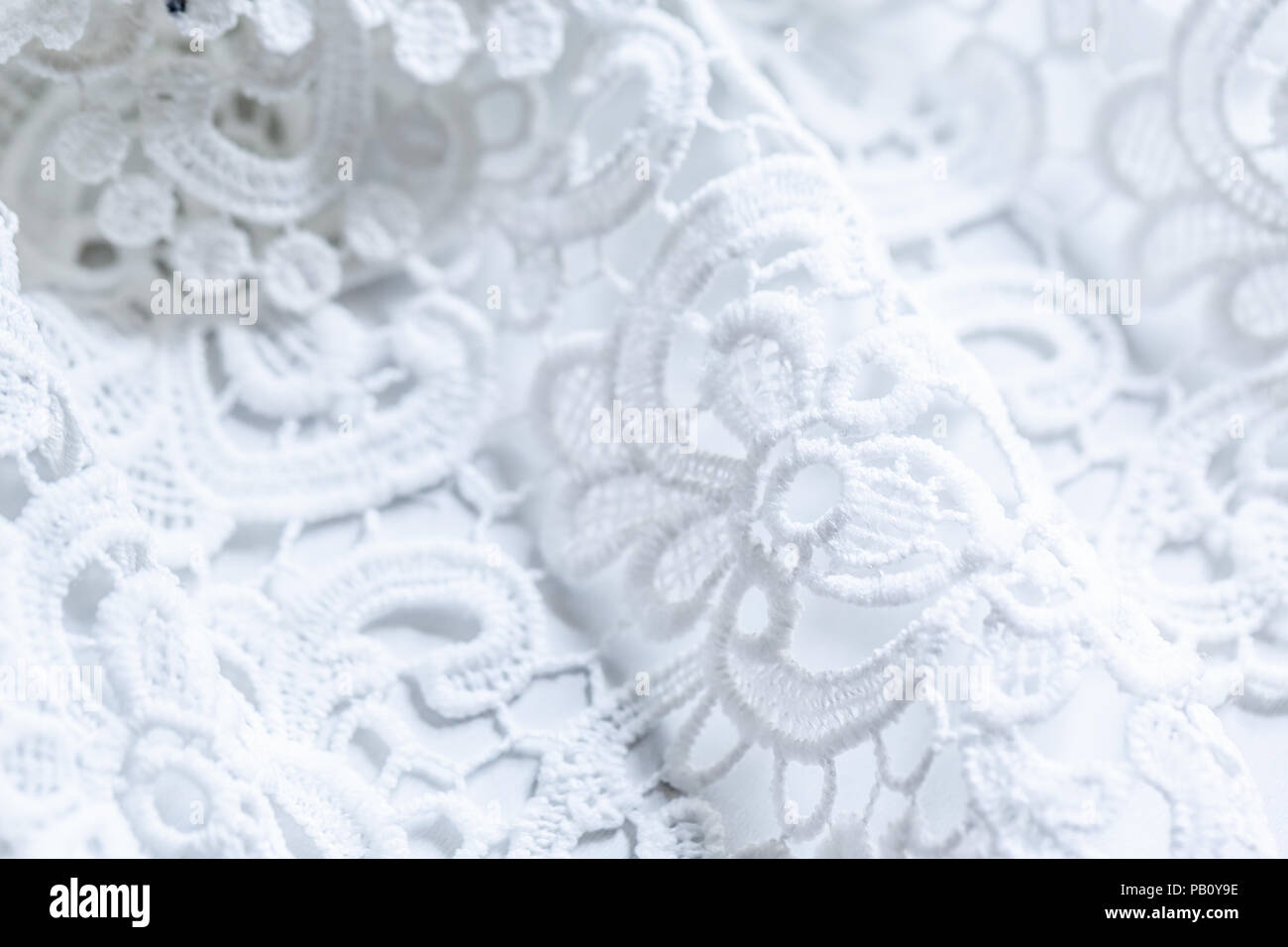 Die Textur der Spitze auf einem weißen Hintergrund. Nahaufnahme des rippled weißen Stoff. Zusammenfassung Hintergrund von luxuriösen Tuch für eine Hochzeit Kleid Stockfoto