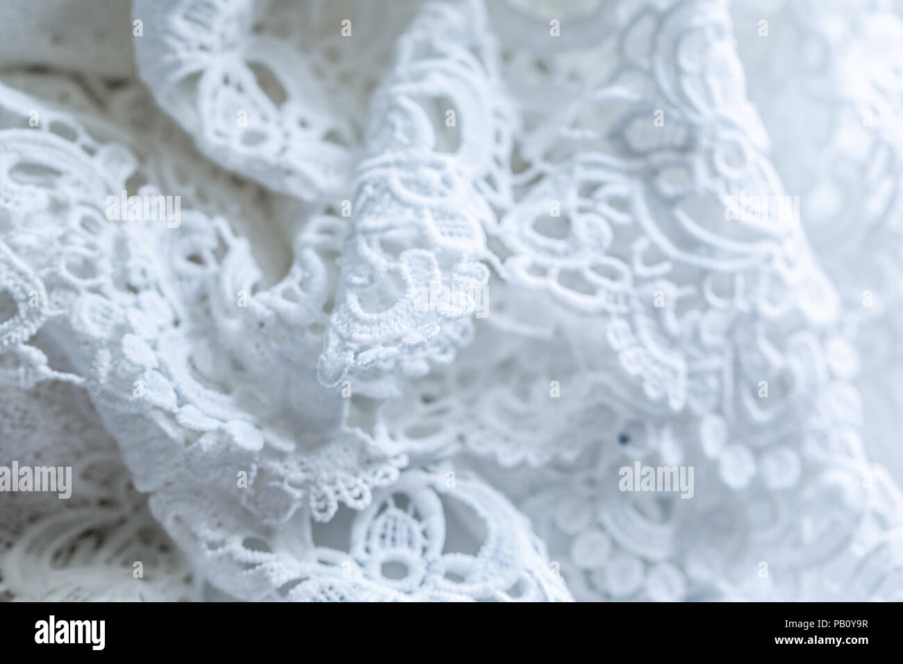 Die Textur der Spitze auf einem weißen Hintergrund. Nahaufnahme des rippled weißen Stoff. Zusammenfassung Hintergrund von luxuriösen Tuch für eine Hochzeit Kleid Stockfoto
