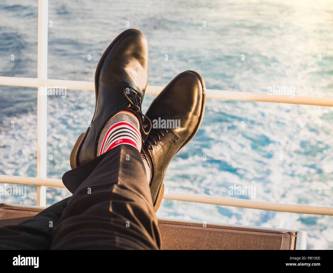 Mann in elegante, schwarze Schuhe, dunkle Hose und lustig, hell, Socken mit  Muster auf dem Deck eines Kreuzfahrtschiffes. Lifestyle, Mode, Spaß  Stockfotografie - Alamy
