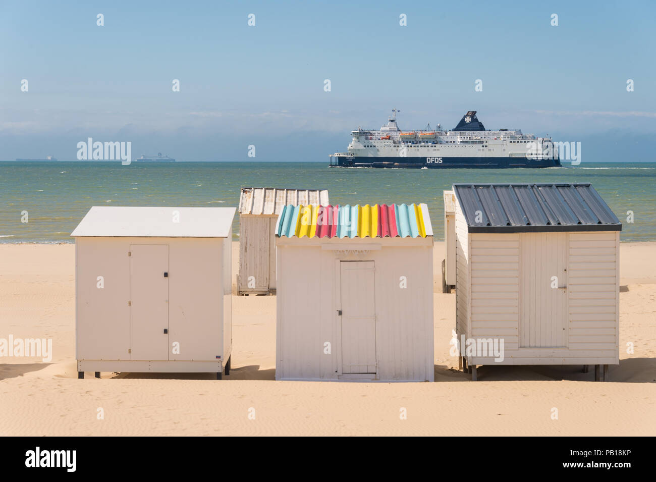 Calais, Frankreich - 19. Juni 2018: Beach Cabins und DFDS Cross Channel Fähre auf dem Weg nach Dover, Großbritannien. Stockfoto