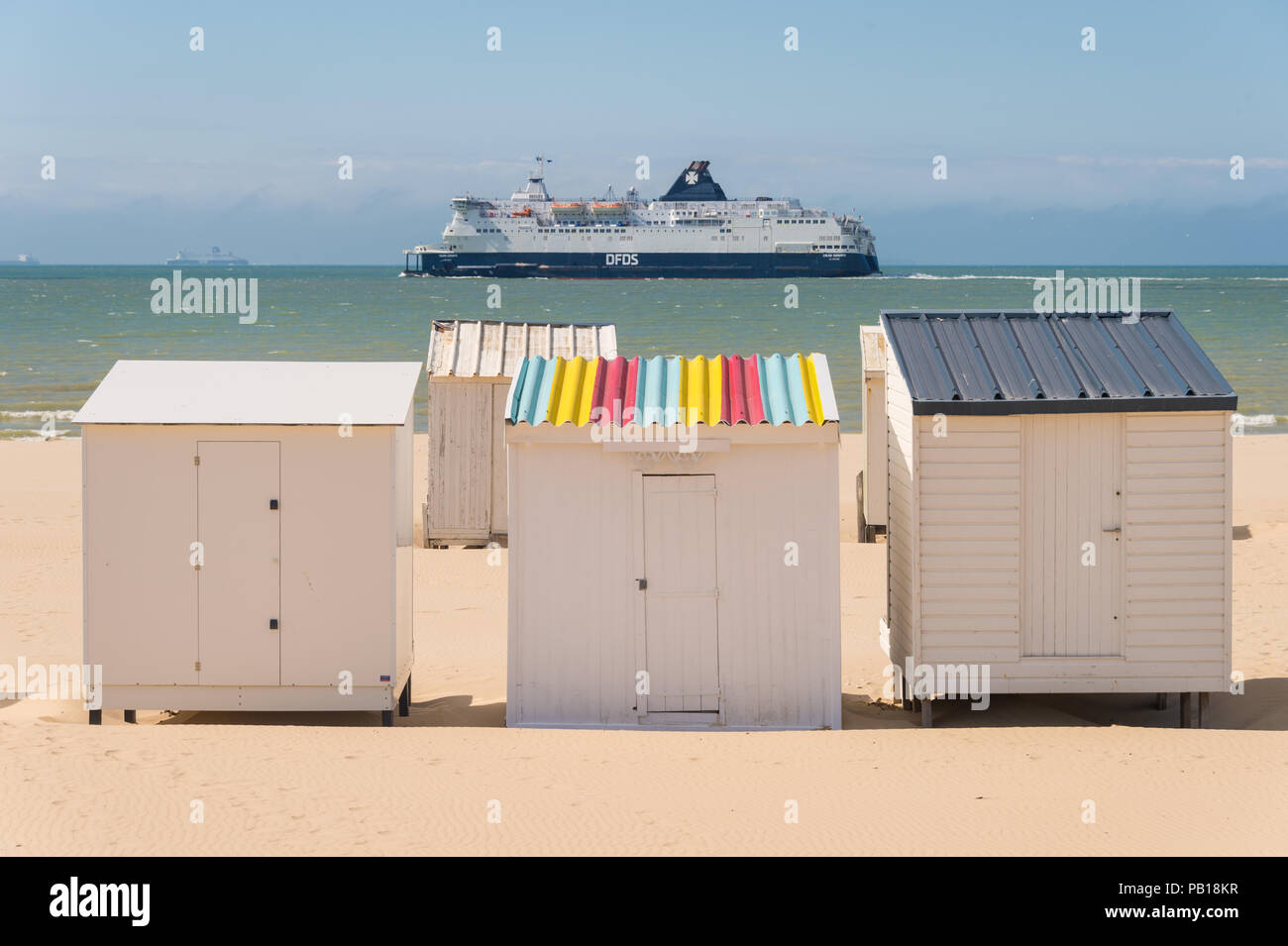 Calais, Frankreich - 19. Juni 2018: Beach Cabins und DFDS Cross Channel Fähre auf dem Weg nach Dover, Großbritannien. Stockfoto