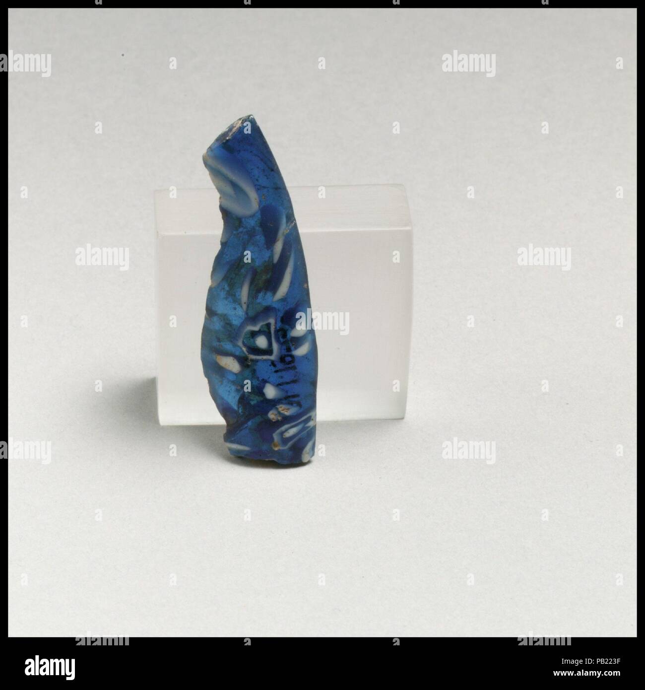 Glas Mosaik Schüssel Fragment. Kultur: Roman. Abmessungen: Andere: 11/16 x 2 1/8 in. (1,7 x 5,4 cm); geschätzte Durchm. Von Rim 7 1/16-in. (18 cm). Datum: Ende 1.Jh. v. Chr. - frühe 1. Jh. N.CHR.. Rim-Fragment, wahrscheinlich aus einem großen gerippt und footd Schüssel. Transluzente Kobaltblau und Deckweiß. Outsplayed, fast horizontale Rim mit der abgerundeten Kante; konkav geschwungenen Hals zu Seite, verjüngt sich nach unten. Composite Mosaik Muster aus polygonalen Abschnitte eines einzigen Stock in einem blauen Boden mit einem Ring von weißen Stangen um einen weißen Kreis und eine zentrale weiße Stange gebildet. Poliert Innenraum; Lochfraß und sligh Stockfoto