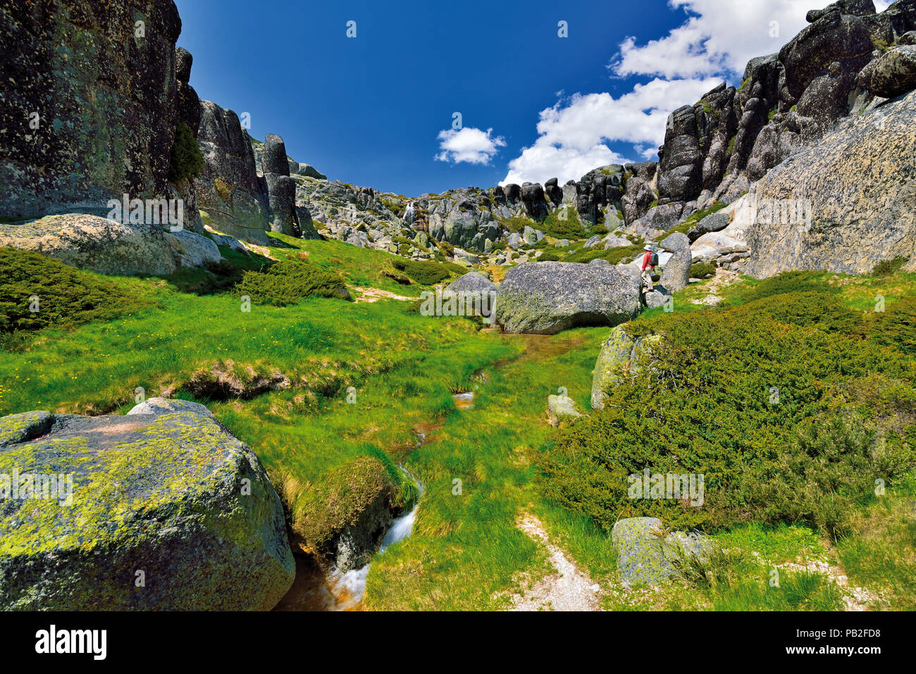 Touristische stehend auf einem Granitfelsen in einem Berggebiet von Granit pics und grüne Vegetation umgeben Stockfoto