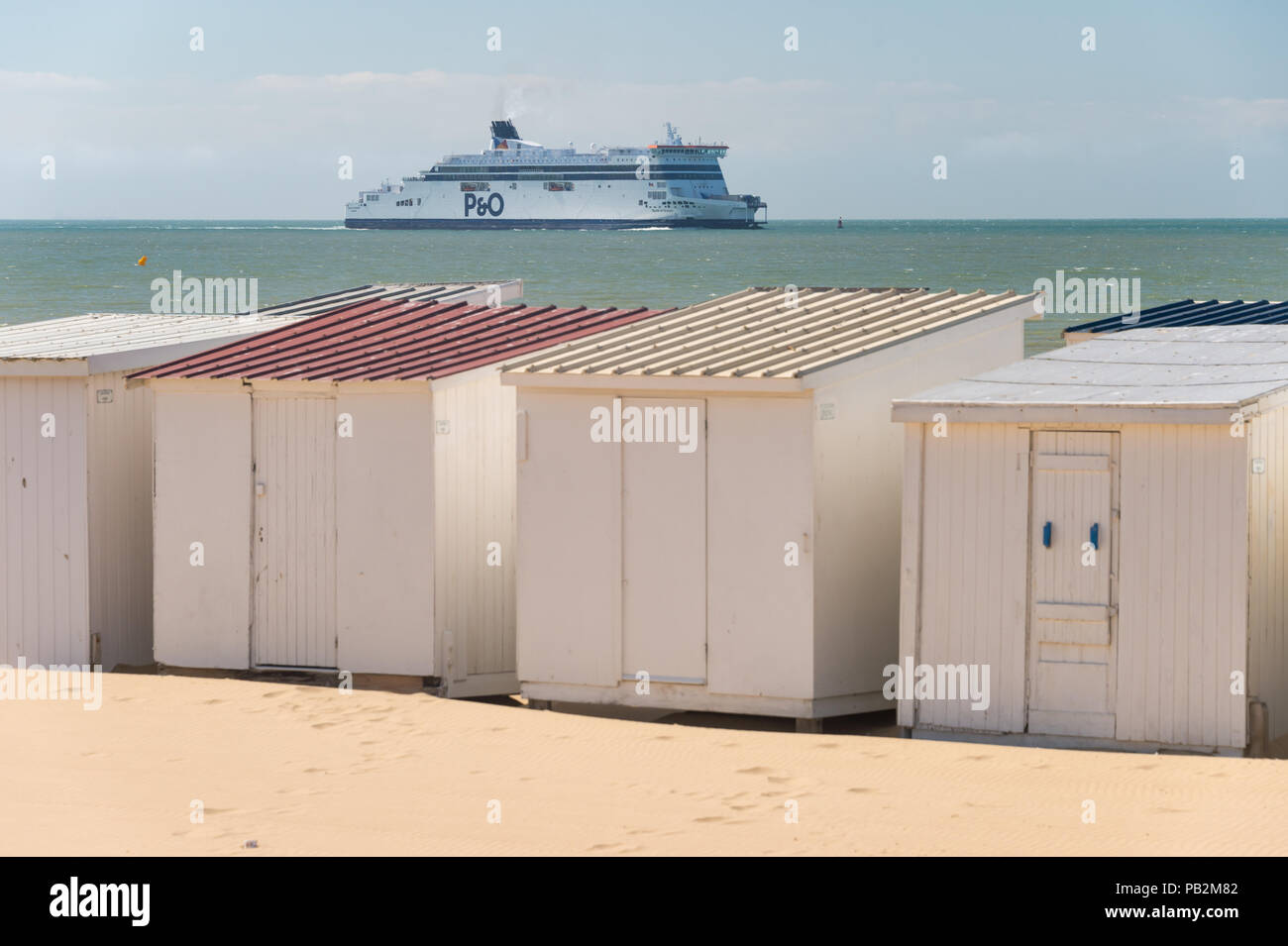 Calais, Frankreich - 19. Juni 2018: Beach Cabins und P&O Cross Channel Fähre auf dem Weg zum Hafen. Stockfoto