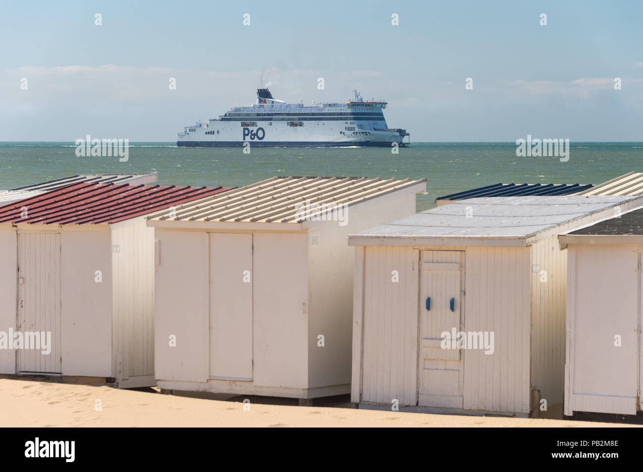 Calais, Frankreich - 19. Juni 2018: Beach Cabins und P&O Cross Channel Fähre auf dem Weg zum Hafen. Stockfoto