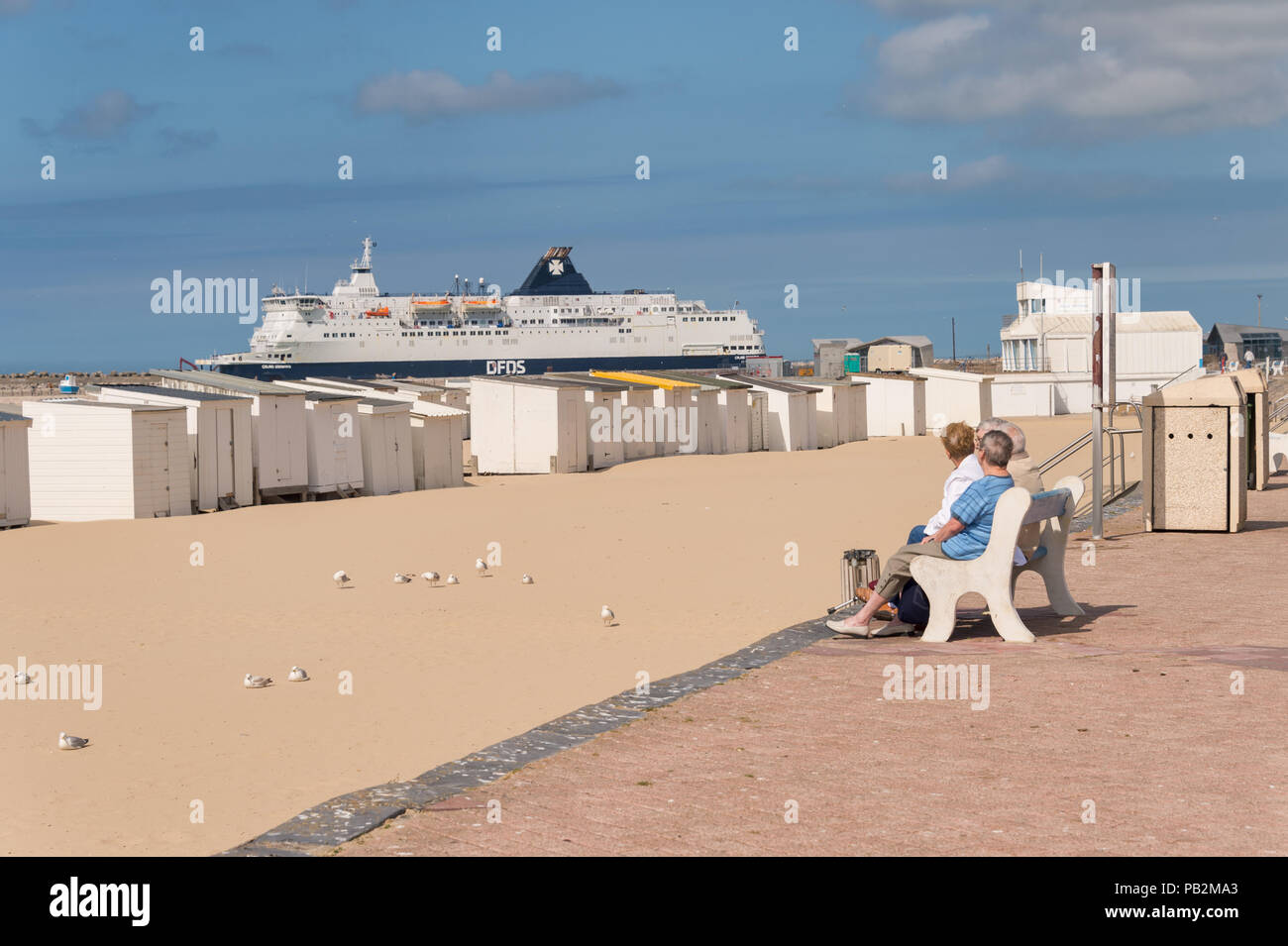 Calais, Frankreich - 19. Juni 2018: Die Menschen sitzen auf einer Bank und schaut auf einen DFDS Cross Channel Fähre aus dem Hafen Stockfoto