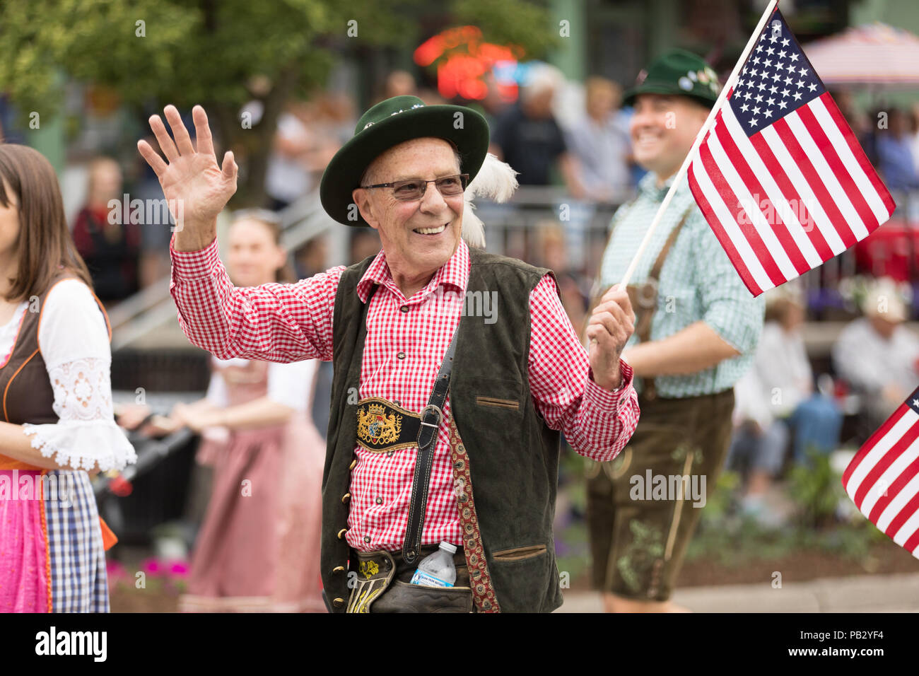 Frankenmuth, Michigan, USA - Juni 10, 2018 Männer und Frauen tragen  traditionelle deutsche Kleidung auf der Straße winken amerikanische Flaggen  an der Bayerischen gehen Stockfotografie - Alamy