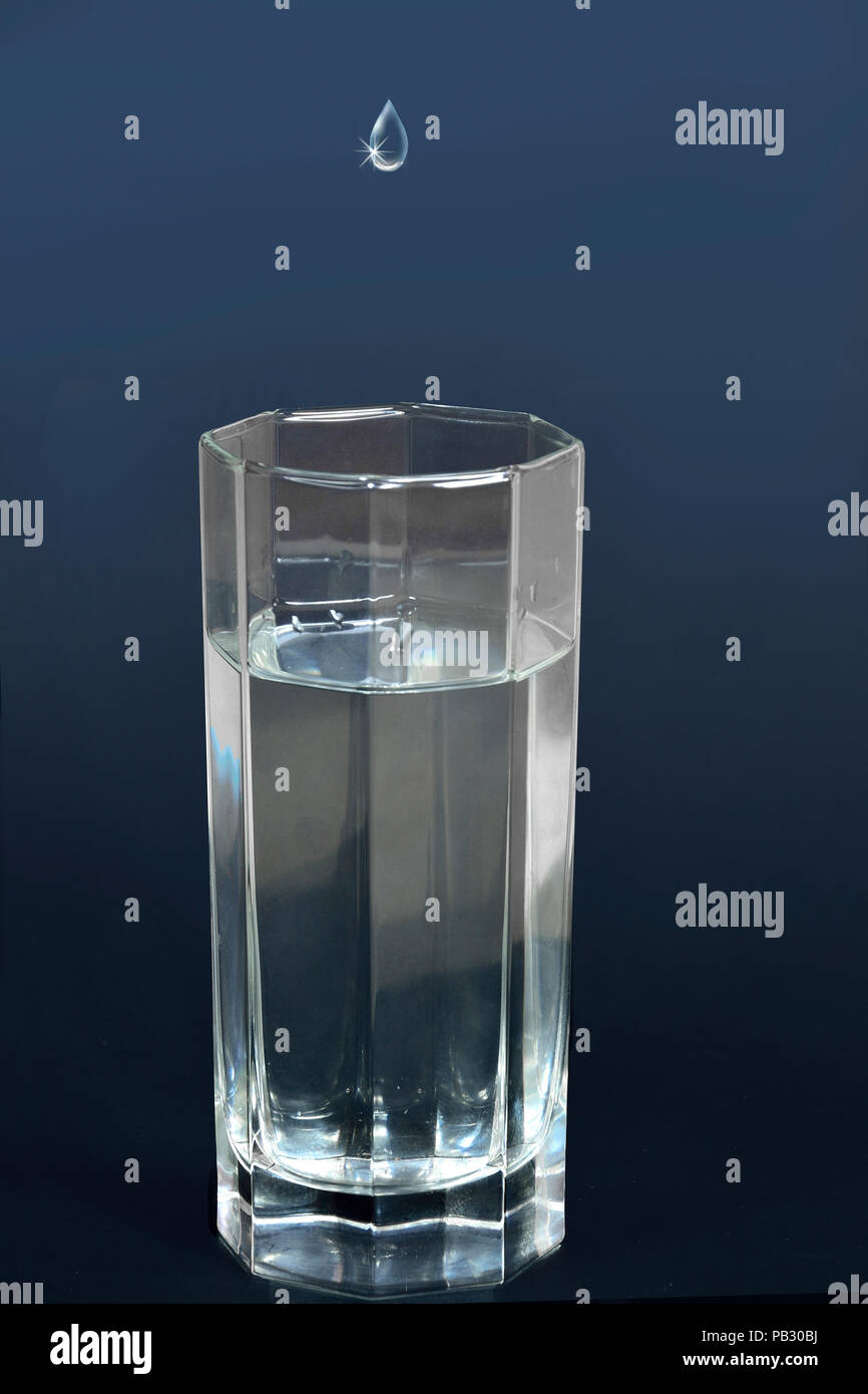 Tropfen Wasser oder andere Flüssigkeit in ein Glas mit einem klaren und erfrischenden Getränk gefüllt fallen Stockfoto
