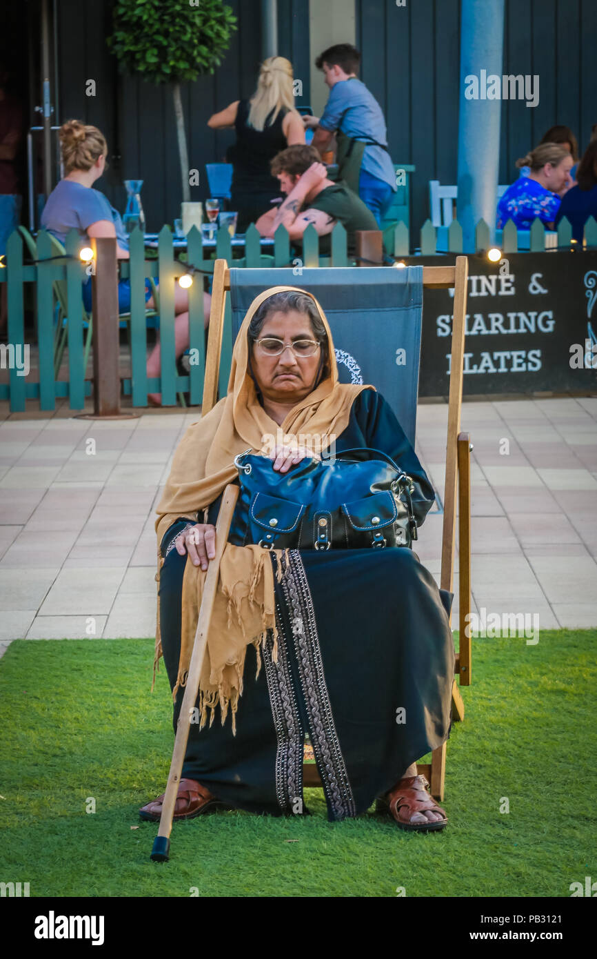 Eine alte asiatische Frau ruht auf einem Liegestuhl an einem heißen Abend Stockfoto