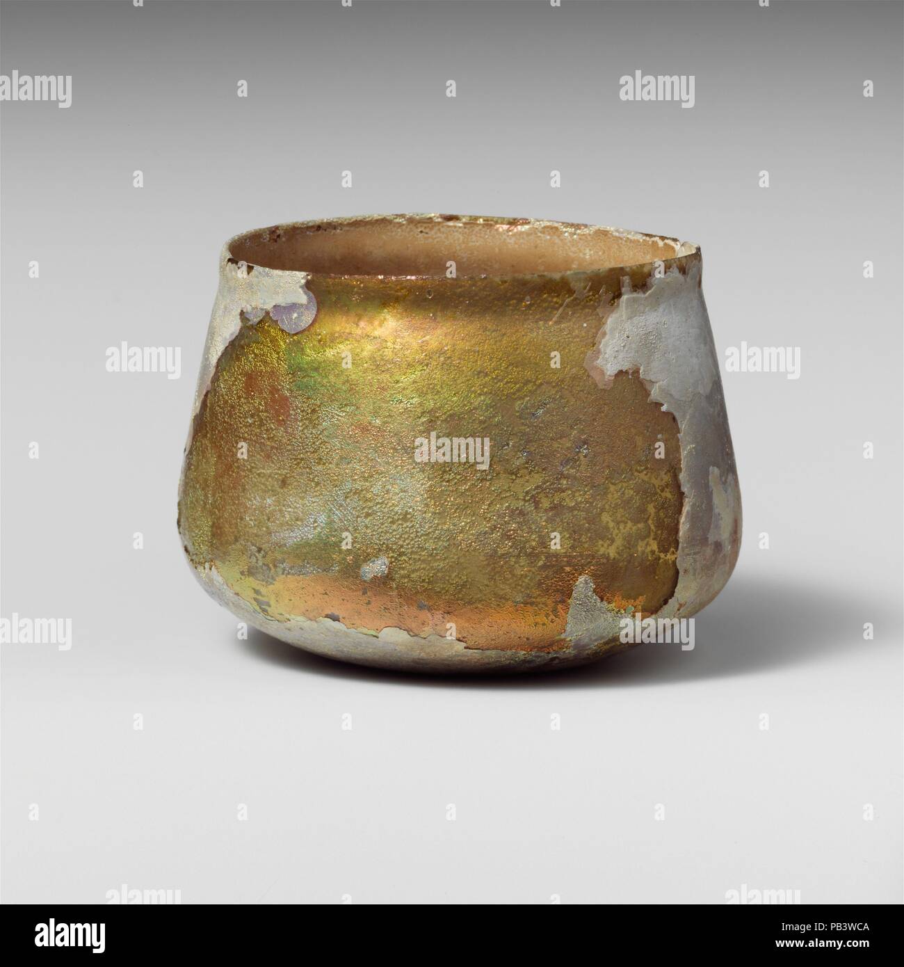 Glas Schale. Kultur: Roman. Abmessungen: Insgesamt: 2 5/8 in. (6.6Cm) Durchm.: 3 1/2 x 2 7/8 in. (8,9 x 7,3 cm). Datum: 2.-3.Jh. N.CHR.. Unsicher, wahrscheinlich farblos mit grünlichen Farbton. Klopfte, unebenen Rand; leicht ausbauchen Kragen unter Rim; Seiten nach unten erweitert, dann schräg in zu melden Sie unten mit leicht konkav. Band von schwachen Rad - Abgerieben horizontale Linien auf den Körper schräg-oben. Abgeschlossen, aber mit großen Riss von RIM, der die Seite nach unten; viele Pinprick blasen; tiefe Rillen und brillante irisierende Bewitterung im Außenbereich; dicke, cremige Braun überstehen auf Interieur. Museum: Stockfoto