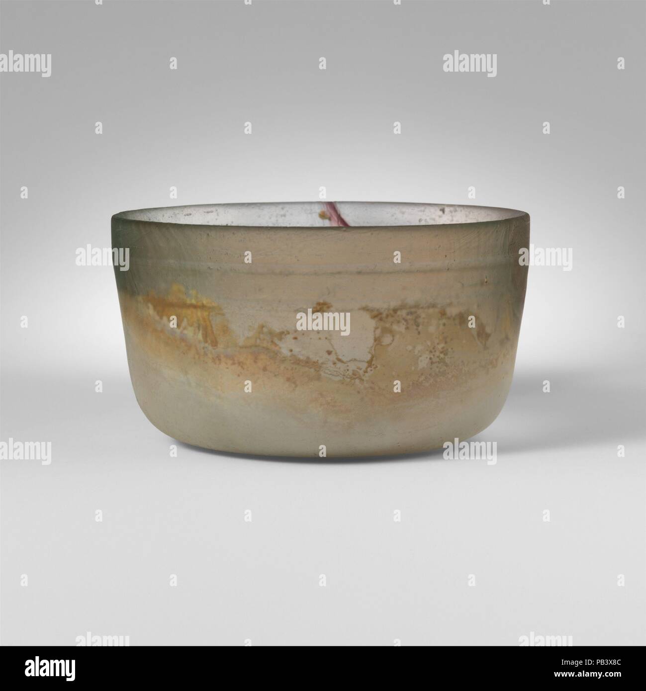 Glasschale. Kultur: Roman. Abmessungen: Insgesamt: 2 3/8 x 4 1/4 in. (6 x 10,8 cm). Datum: Ende 1.Jh. v. Chr. - frühe 1. Jh. N.CHR.. Farblos mit blass grünlich Tönung, und einer violetten Streifen auf einer Seite. Abgerundet vertikale Rim; Seiten nach unten verjüngt, dann gebogen zu flachen Boden. Zwei große, horizontale Rad - Nuten auf der Innenseite unten Rim schneiden. Intakt; viele pinprick Blasen und Schlieren; Mattierung und Lochfraß auf äußere, Patches von dicken, cremigen braun Überstehen auf Interieur. Blaues Glas Schale mit Linien. Museum: Metropolitan Museum of Art, New York, USA. Stockfoto