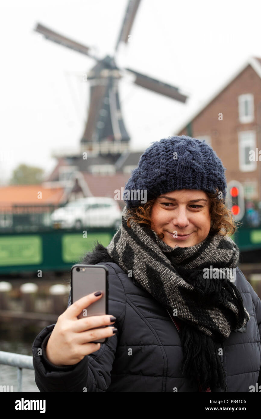 Eine Frau nimmt eine selfie in von = nt der De Adriaan Mühle (Molen de Adriaan) in Haarlem, Niederlande. Stockfoto