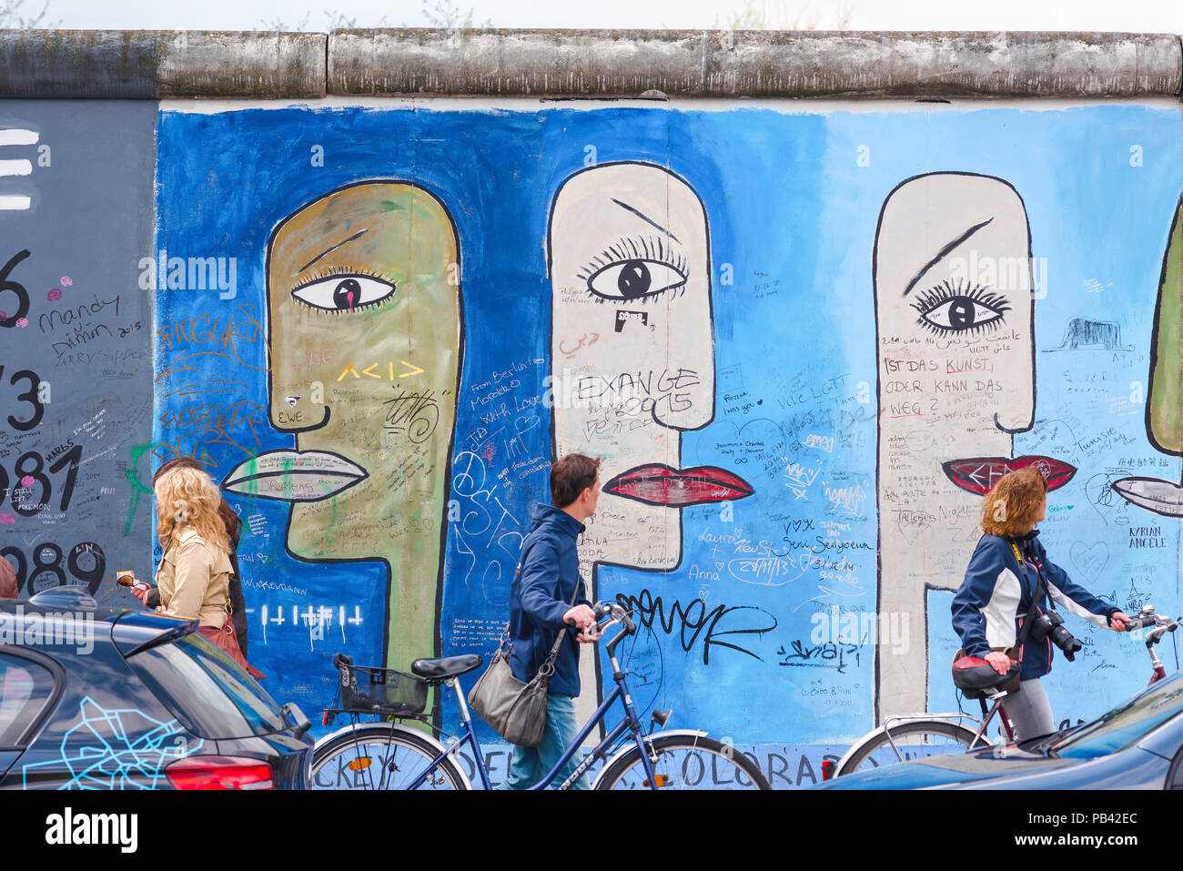 Berliner Mauer, Blick auf die Menschen, die ihre Fahrräder Vergangenheit ein buntes Teil der East Side Gallery an der Wand in Frederichshain, Berlin, Deutschland. Stockfoto