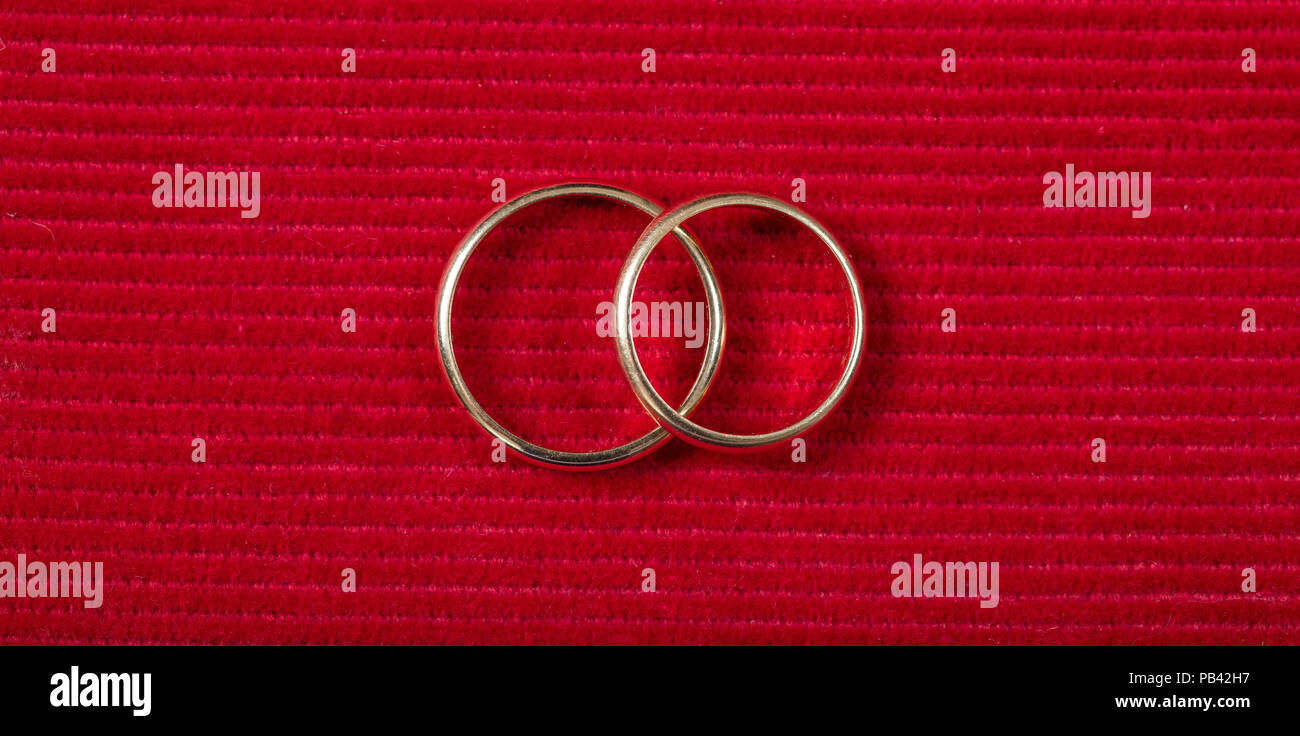 Ein paar goldene Hochzeit Ringe auf rotem Hintergrund, Ansicht von oben Stockfoto