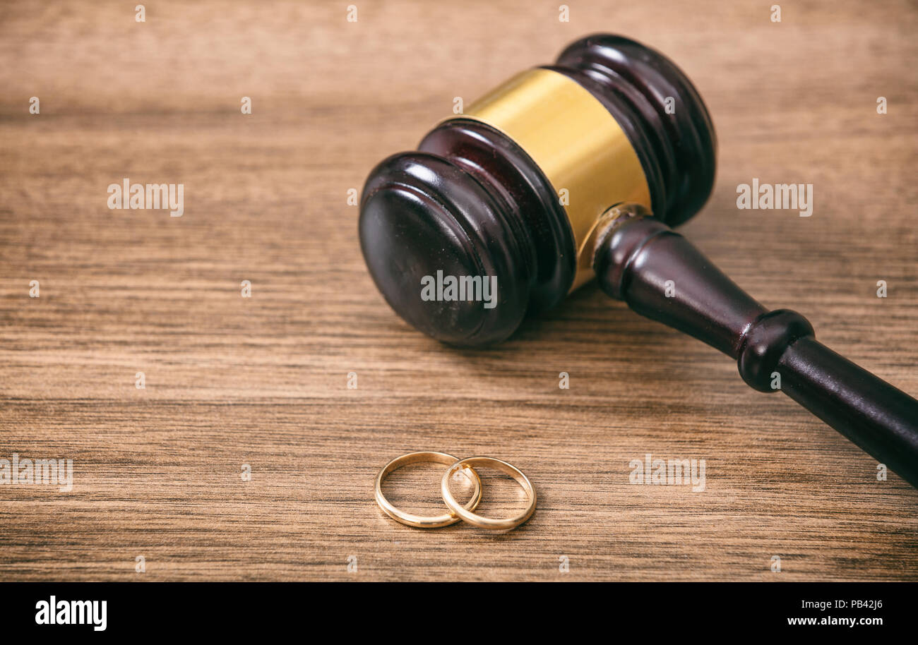 Scheidung Konzept. Trauringe und Richter Hammer auf hölzernen Hintergrund Kopie Raum Stockfoto
