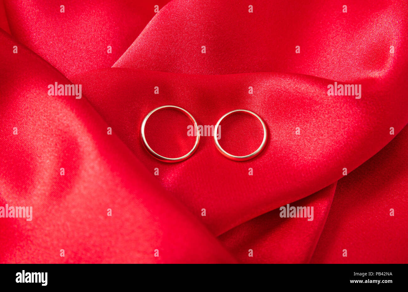 Ein paar goldene Hochzeit Ringe auf rotem Satin Hintergrund, Ansicht von oben Stockfoto