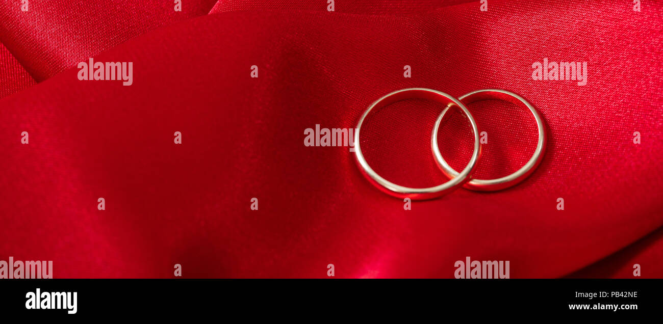 Ein paar goldene Hochzeit Ringe auf rotem Satin Hintergrund, Banner, kopieren Raum Stockfoto