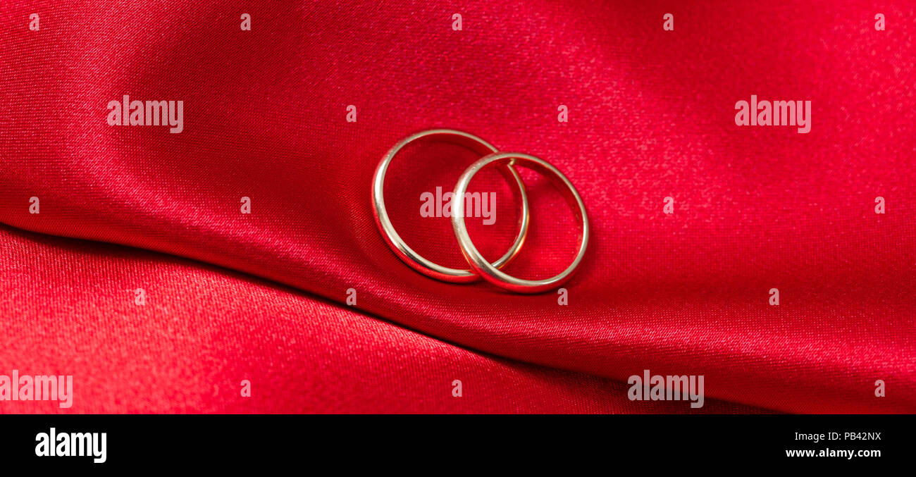 Ein paar goldene Hochzeit Ringe auf rotem Satin Hintergrund, Banner Stockfoto