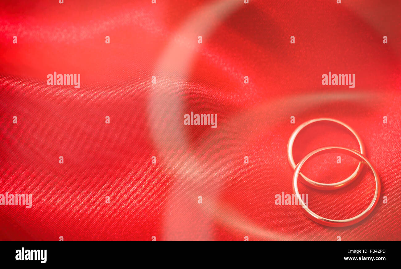 Ein paar goldene Hochzeit Ringe auf rotem Satin Hintergrund, Ansicht von oben Stockfoto