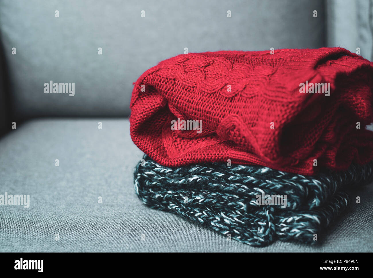 Horizontale, warme Pullover auf grau Couch, saisonale Konzept, Herbst Winter Outfit, bei kaltem Wetter Stockfoto