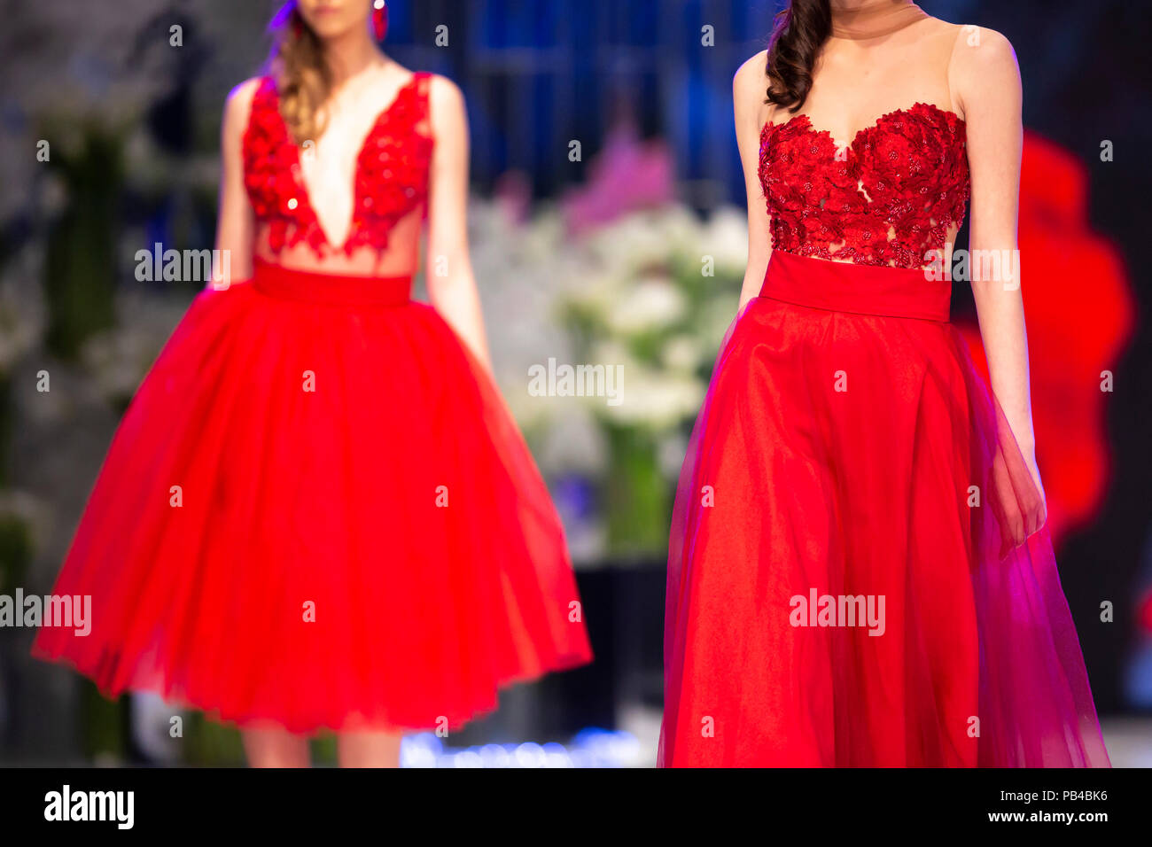 Weibliche Modelle gehen Sie die Start- und Landebahn in roten Kleidern während einer Modenschau. Fashion Catwalk Ereignis zeigt neue Sammlung von Kleidung. Stockfoto