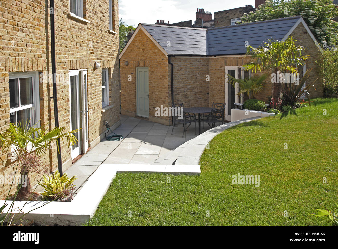 Ein erweitertes viktorianisches Haus in Süd- London, Großbritannien, zeigt neue, Ziegel - Garten Zimmer durch einen erhöhten Garten umgeben. Stockfoto