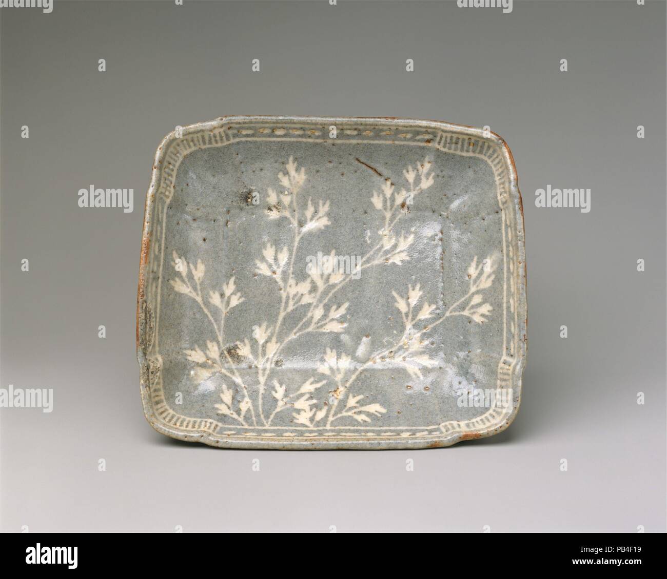 Schale mit Gräsern. Kultur: Japan. Abmessungen: H.2 3/8 in. (6 cm); W. 8 3/8 in. (21,3 cm); D.7 1/4 in. (18,4 cm). Datum: Ende des 16. Anfang des 17. Jahrhunderts. Sprays der Herbst Gräser sind auf dem Platz Oberfläche dieses Gericht dargestellt. Der äußere Rand, mit Bands von abstrakten Mustern gestaltet - kurzen vertikalen Balken um die Ecken und horizontale Striche an den Seiten - ist wie ein Rahmen für ein Gemälde. Das Stück wurde zunächst nicht mit einem Rad gebildet, sondern durch Drücken der Taste ein Ton Scheibe über eine Art von Schimmel. Die Seiten der Teller wurden sanft nach oben und seine Ecken gerundet und mit Vertiefungen geformt. Vier Stockfoto