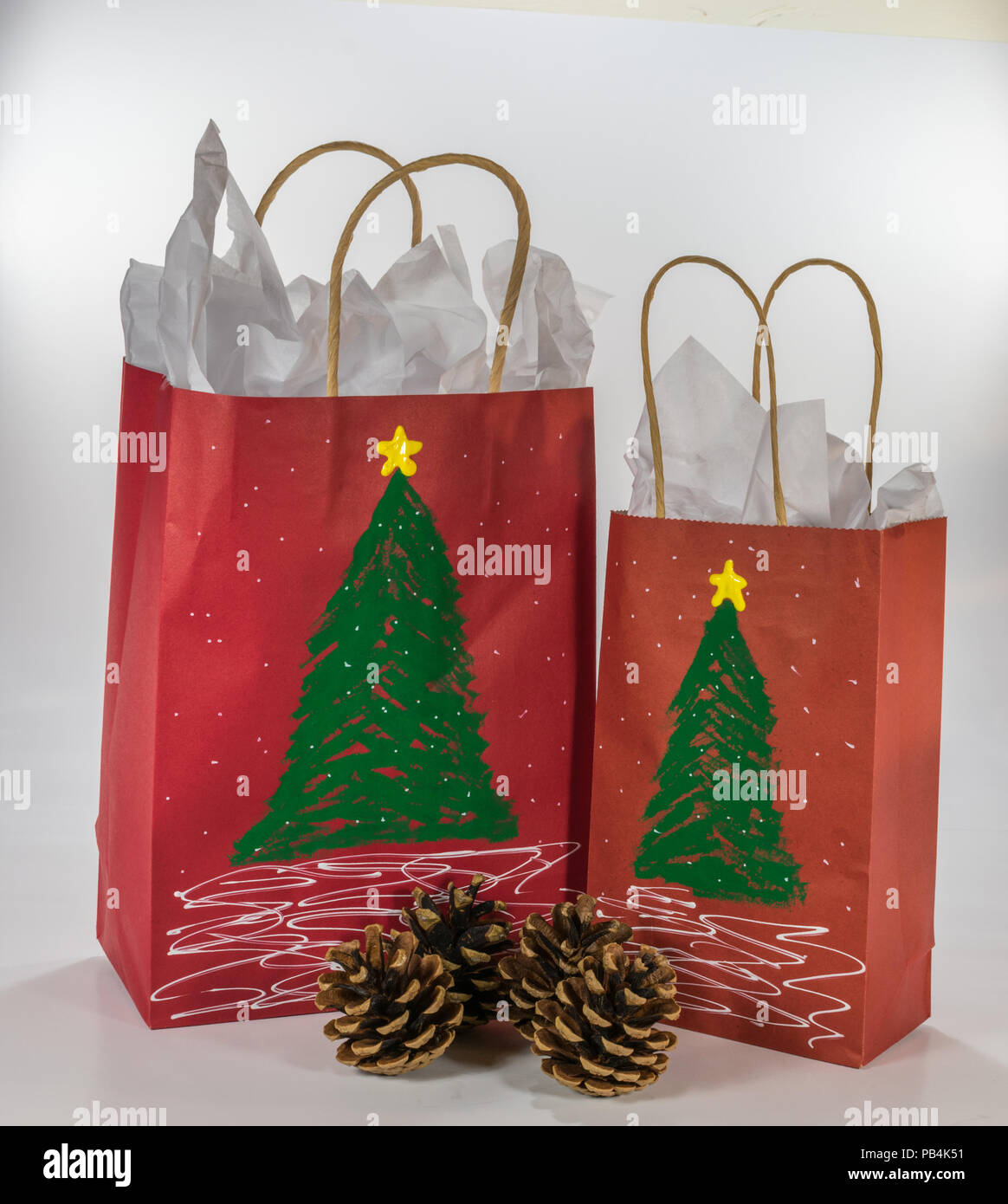 Zwei rote Gift Bags für Weihnachten dekoriert und bereit für zusammen mit vier Tannenzapfen Stockfoto