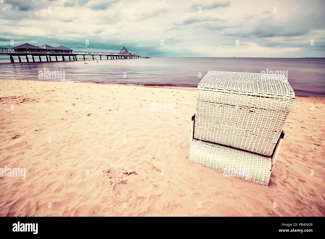Vintage getonten Bild eines hooded Weidenkorb Stuhl am Strand. Stockfoto