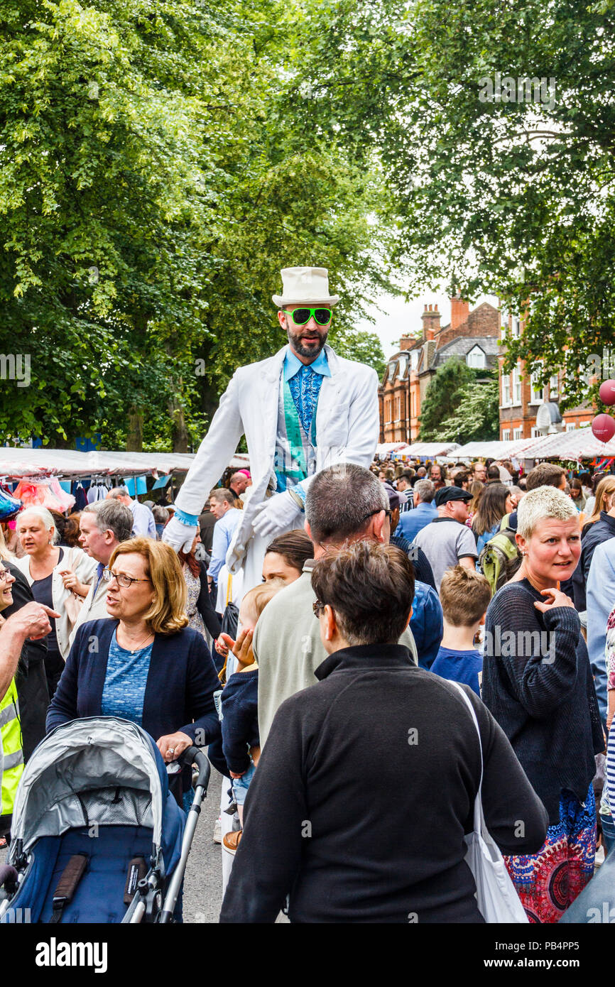 Mann in einem weißen Anzug auf Stelzen am "Fair auf dem Platz", ein jährliches Festival im Teich Square und South Grove, Highgate, London, UK Stockfoto