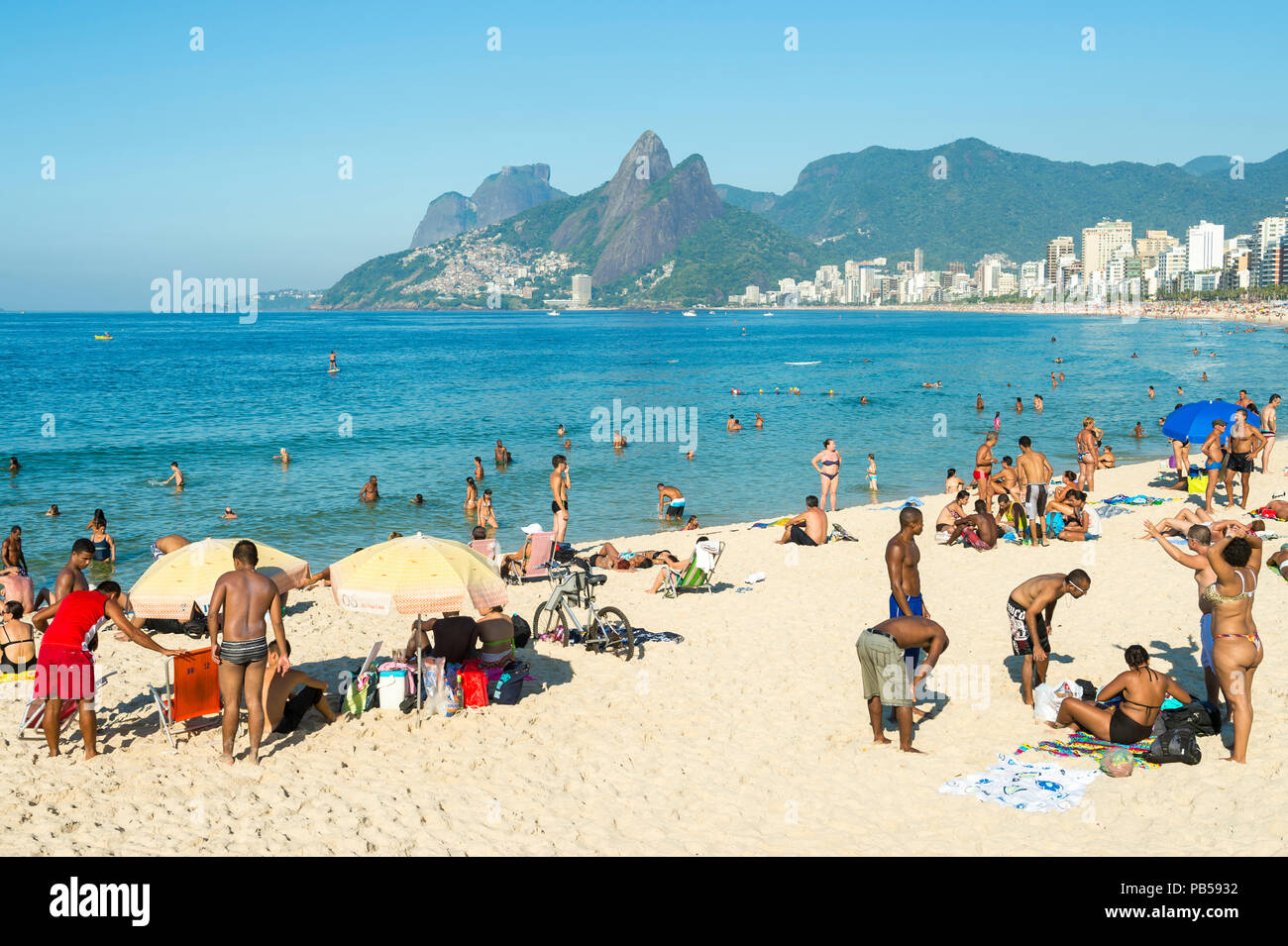 RIO DE JANEIRO, Brasilien - 26. Januar 2014: Rio Einwohner, bekannt als Cariocas, entspannen Sie sich im Abschnitt Arpoador von Ipanema Beach Stockfoto