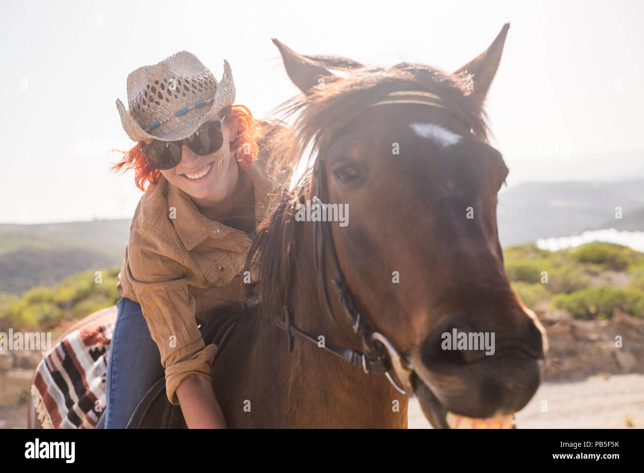Schöne fröhliche junge Frau genießen ihre braunen süße Pferdchen in Freundschaft und Beziehung reiten. Tierliebhaber und pet-Therapie Konzept. Reisen und Va Stockfoto
