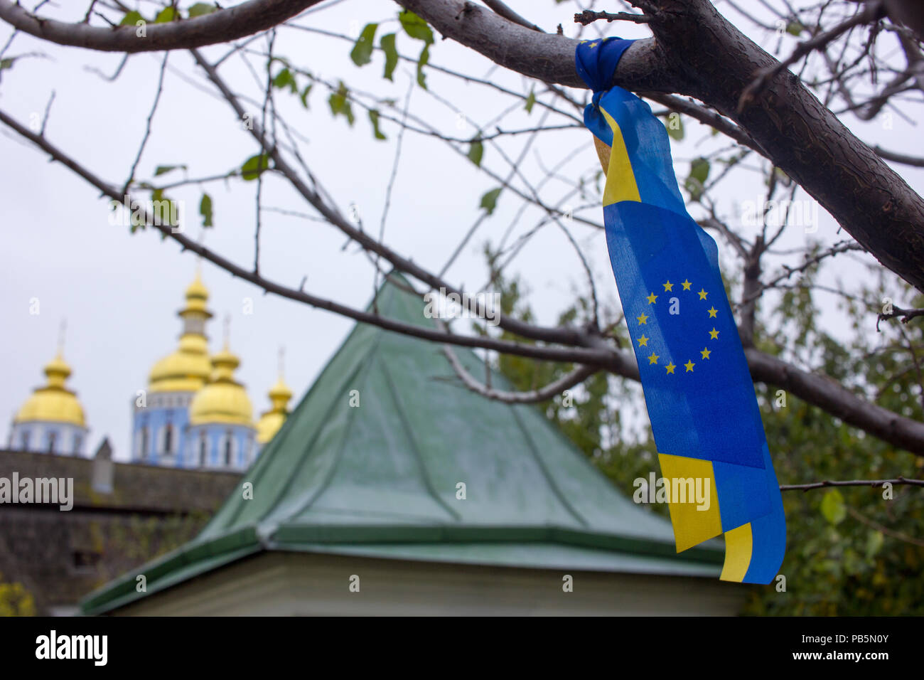 Blau und Gelb Ukraine-EU-Band auf einem Baum in Kiew mit goldenen Kirchenkuppeln im Hintergrund Stockfoto