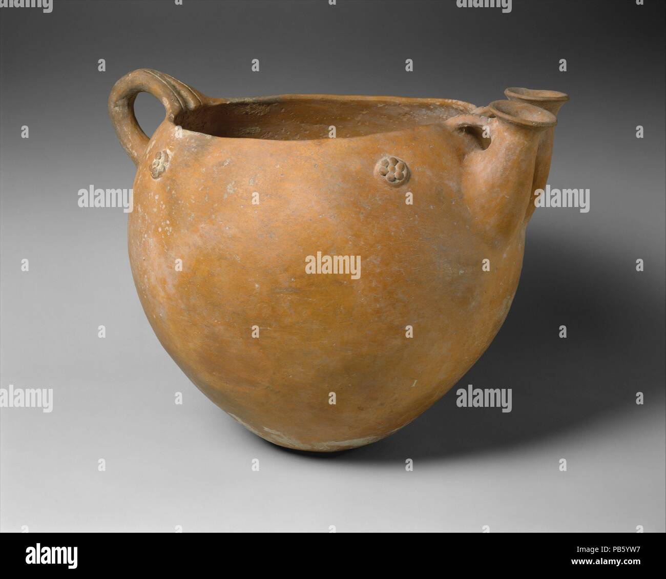Terrakotta Schüssel. Kultur: Zypriotische. Abmessungen: H 14. (35,6 cm) Durchmesser 10 cm. (27,6 cm). Datum: Ca. 2500-1600 v. Chr.. Schüssel mit Griff und zwei Tüllen. Rot poliert Ware Schiffe, wie diese Schüssel, machte ihr Aussehen ganz am Anfang der ersten zypriotischen ich Periode, die von Einwanderern aus Anatolien, die auf der Insel bald nach der Mitte des dritten Jahrtausends v. Chr. die Oberfläche mit einem roten Slip, die dann brüniert wurde ein glänzendes Aussehen zu rendern abgedeckt wurde eingeführt. Die kleinen Rosetten und Einschnitte am Griff, gefüllt mit Kalk nach dem Feuern, verleihen einen Strik Stockfoto