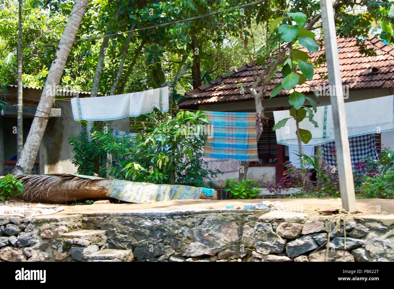Wäscheleine mit frisch gewaschene bunte traditionelle indische Kleidung in den Wind hängen an einem sonnigen Sommertag in der Landschaft von ländlichen Kerala Stockfoto