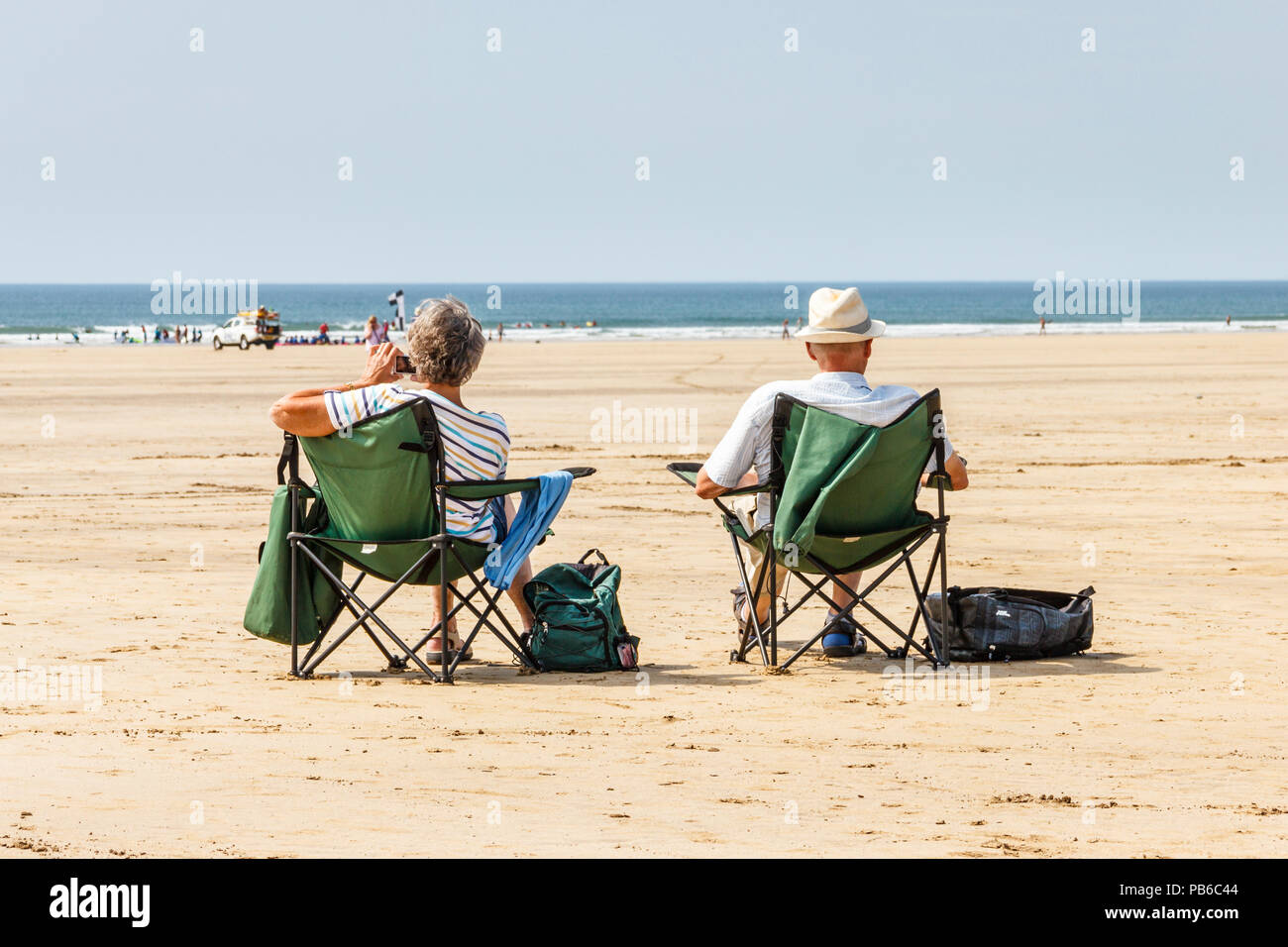 Zwei ältere Urlauber (Mann und Frau) in Liegen auf der Suche nach Sonne und Meer als die Sommerhitze fort, Westward Ho!, Devon, Großbritannien Stockfoto