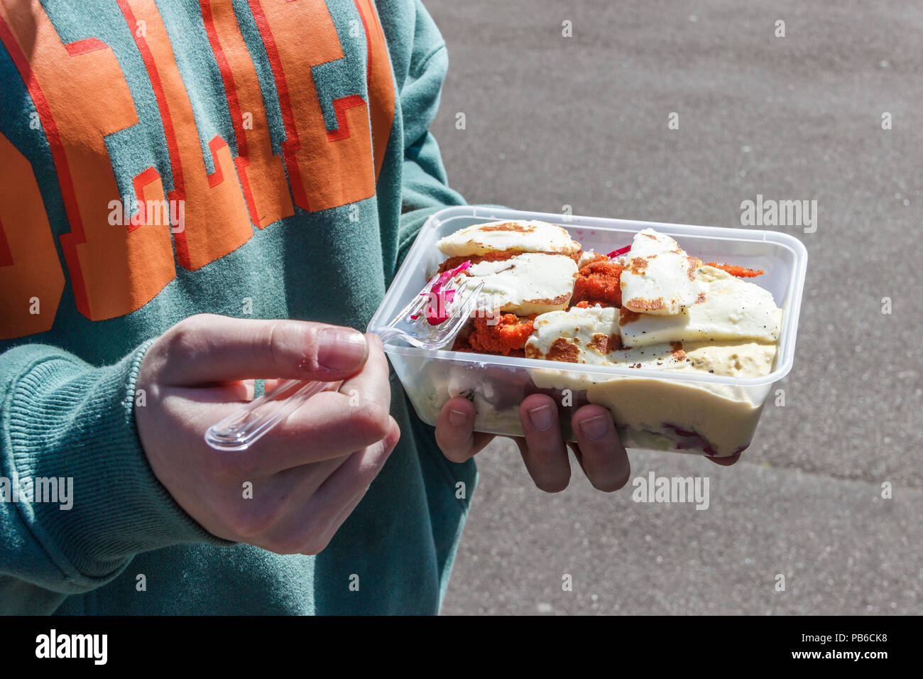 Teenager Essen zum Mitnehmen Halloumi und Chicken Salat auf der Straße Stockfoto