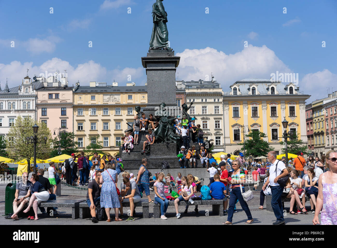 Polnische Kinder sitzen und ruhen auf dem Adam Mikiewicz Denkmal auf dem Hauptplatz in Krakau, Polen, Europa. Stockfoto