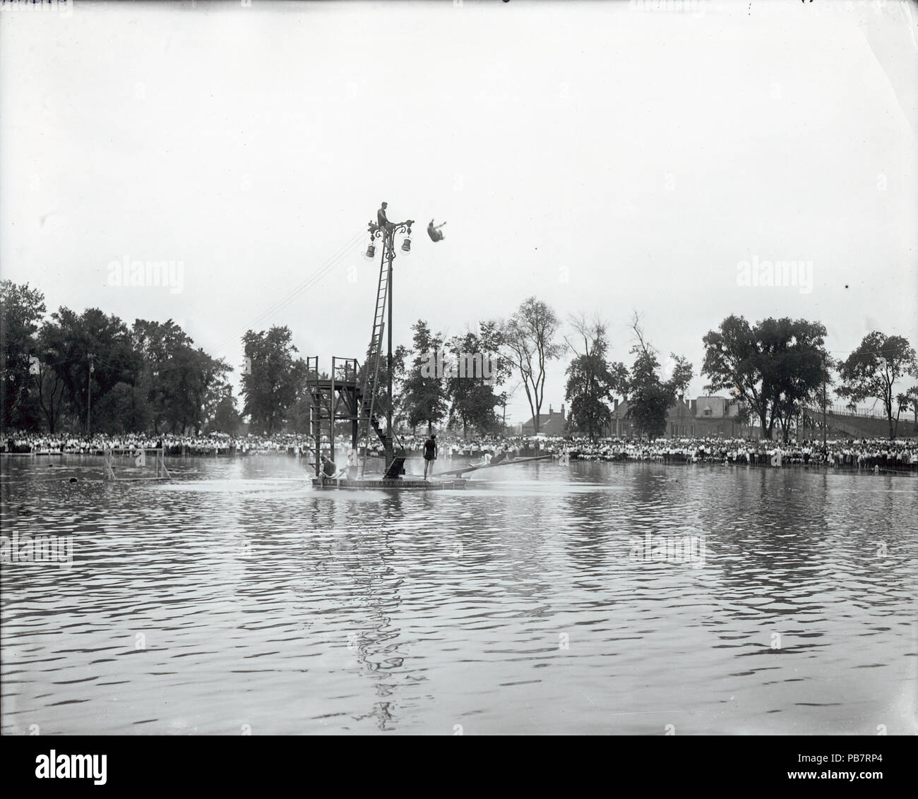921 Rettungsschwimmer Aufstieg an die Spitze der light Standard neben dem sprungturm auf Jahrmärkten Park Schwimmbad etwas extra hohe Tauchgänge zu zeigen Stockfoto