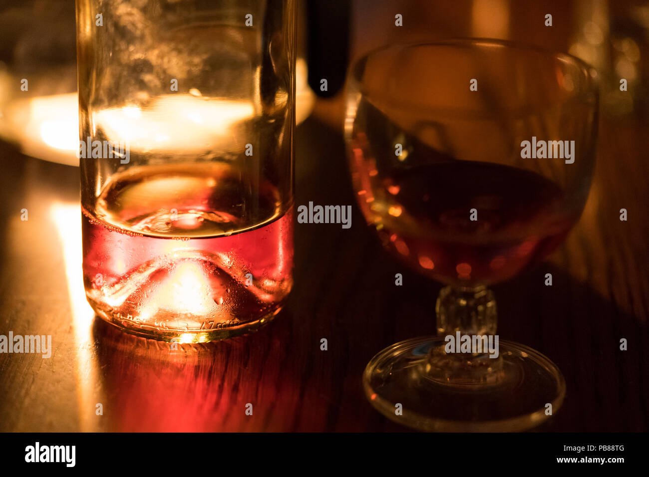 Mit einer fast leeren Flasche Wein und einem Glas Wein bei Kerzenschein beleuchtet Stockfoto
