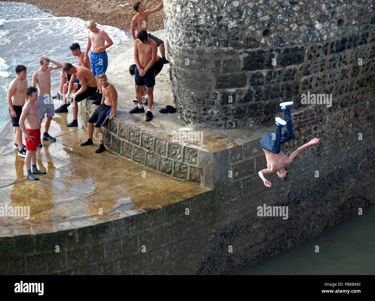 Jugendliche ins Meer springen von einem groyne in Brighton Stockfoto