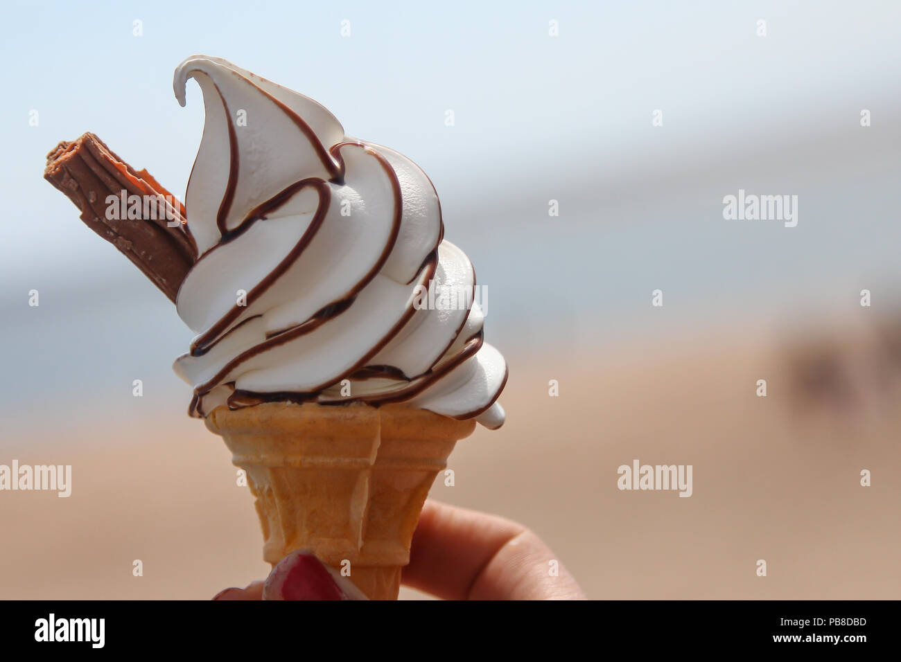 Ein Eis mit einem Flake und Schokoladensauce am Meer. Stockfoto