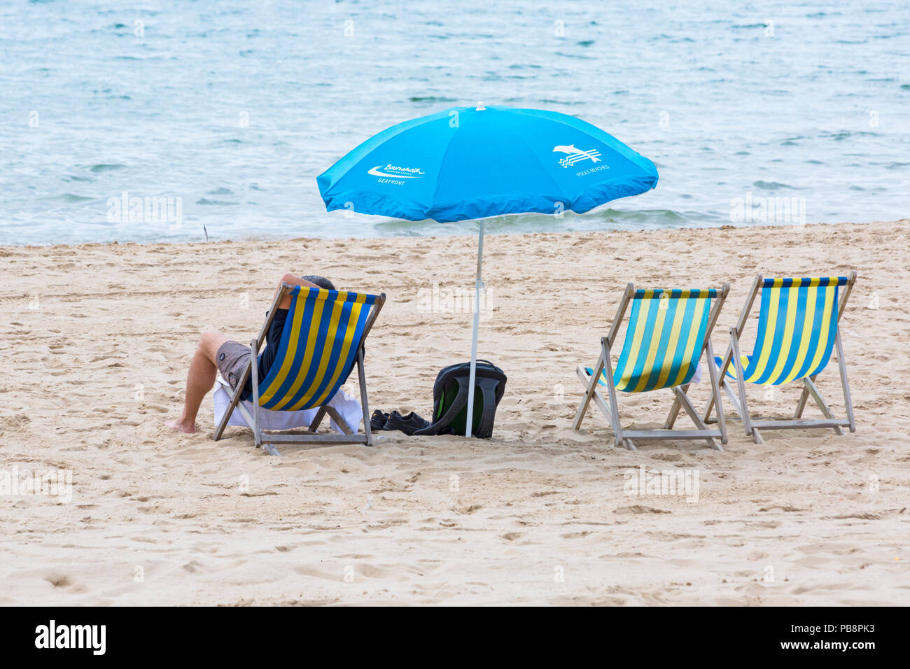 Bournemouth, Dorset, Großbritannien. 27. Juli 2018. UK Wetter: Sunseekers Kopf am Meer in der Sonne am Bournemouth Strände an einem warmen feuchten Tag mit etwas Bewölkung zu tränken. Entspannen im Liegestuhl mit Sonnenschirm am Strand. Credit: Carolyn Jenkins/Alamy leben Nachrichten Stockfoto