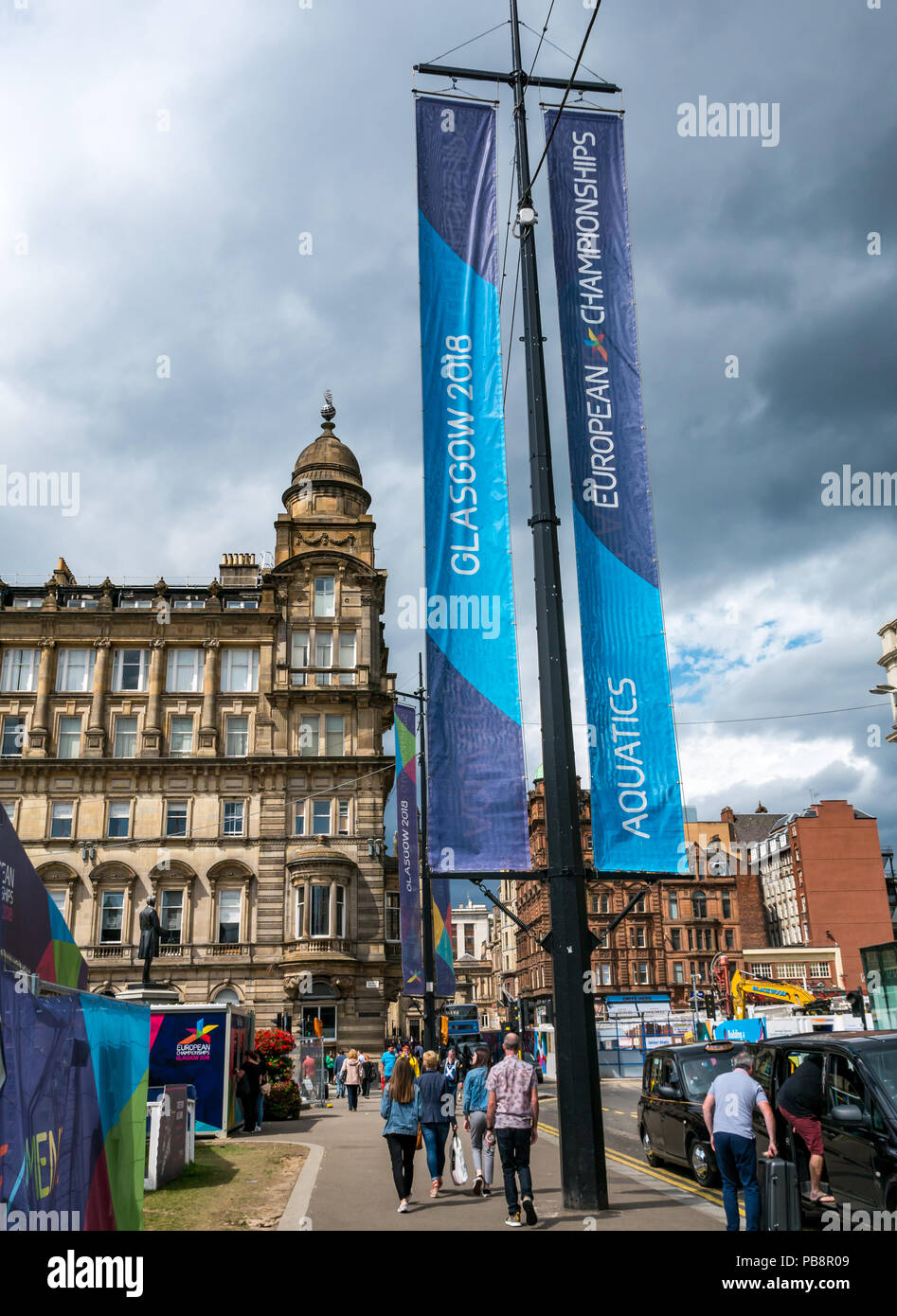 Glasgow Em-Vorbereitungen, den 27. Juli 2018. Glasgow und Berlin Gastgeber der Eröffnungs-Europameisterschaften Sport Event mit führenden Sportarten wie Leichtathletik, Wassersport, Radfahren, Turnen, Rudern, Triathlon mit einem neuen-Meisterschaften. Die Spiele werden alle vier Jahre ausgetragen werden ab August 2-12 Th 2018. Große Banner Werbung die Spiele mit dem spire von Glasgow City Chambers gegen einen verdunkelnden Himmel mit Gewitterwolken Stockfoto