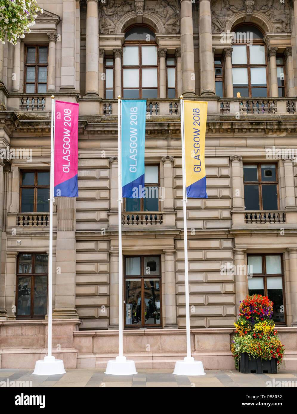 Glasgow, UK. 27. Juli 2018. Glasgow Em-Vorbereitungen, den 27. Juli 2018. Glasgow und Berlin Gastgeber der Eröffnungs-Europameisterschaften Sport Event mit führenden Sportarten wie Leichtathletik, Wassersport, Radfahren, Turnen, Rudern, Triathlon mit einem neuen-Meisterschaften. Die Spiele werden alle vier Jahre ausgetragen werden ab 12. August 2018. Große bunte Banner Werbung für die Spiele außerhalb von Glasgow City Chambers mit blumenkörben eingerichtet Stockfoto