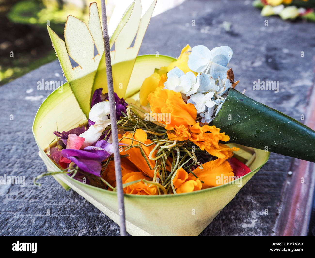 Balinesische canang Sari mit orange Blumen und ein Räucherstäbchen, Besakih Tempel, Bali, Indonesien Stockfoto Balinesische canang Sari mit orange Blumen und ein Räucherstäbchen, Besakih Tempel, Bali, Indonesien Stockfoto